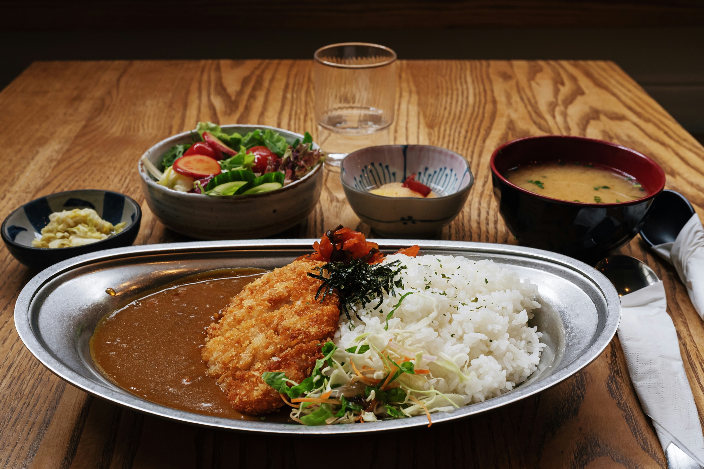 木のテーブルに並んだカレー定食